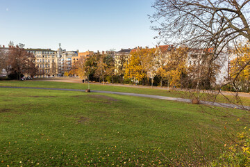 Horizontal wide view of a hill in the Viktoriapark (Eng. Victoria Park), in the locality of Kreuzberg. In the background, buildings of the Kreuzbergstrasse behind yellow foliage