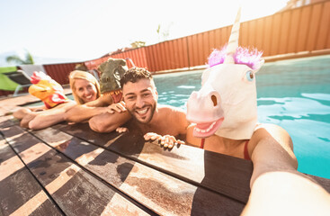 Crazy friends selfie doing pool party wearing bizarre mask - Young people having fun celebrating...