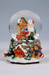 Christmas snow globe ornament set against a grey background.