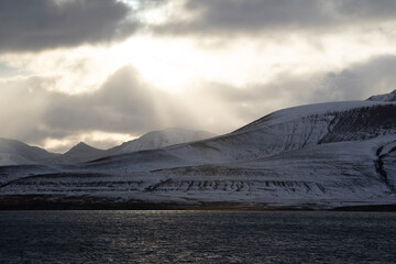 Fjord in the Arctic in the summer on Spitsbergen. Warm light with sun beams over the snow covered...