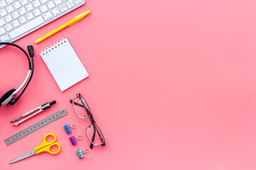 E-learning. Stationery, headphones and keyboard on pink table top-down frame copy space