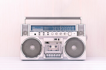 80's retro cassette radio in silver colour on light wood background. Play music concept.
