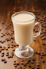 Delicious caffe latte on a wood background surrounded by roasted coffee beans.