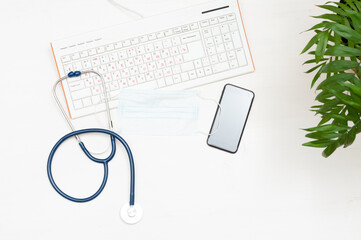 Online medicine. Top view of a wooden table: keyboard, stethoscope, mobile phone. Doctor's workplace