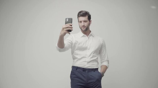 Young handsome businessman isolated on gray background using phone. Selfie time 