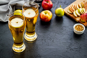 Glasses of beer with apple and peer on black table copy space