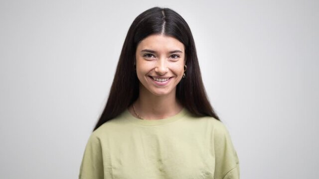 Portrait of young beautiful beautiful cheerful smiling girl looking at camera on grey background.