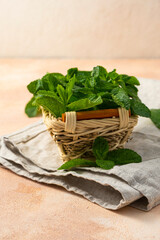sprigs of green fresh mint in a wicker basket on a light background