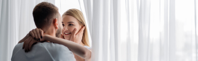 panoramic concept of happy woman hugging man at home