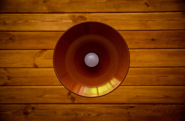 metal chandelier with a white light bulb on a wooden ceiling