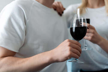 cropped view of man and woman holding glasses with red wine