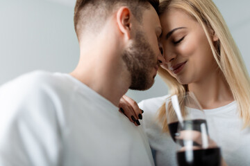 selective focus of happy man and woman with closed eyes holding glasses with red wine