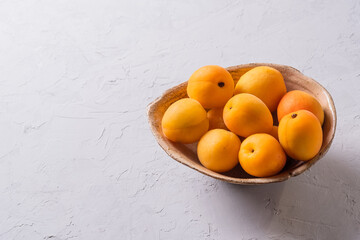 many fresh ripe orange apricots on a  clay plate on a background of a dark wooden table