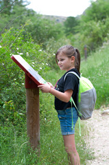Niña en una excursión de senderismo lee un mapa