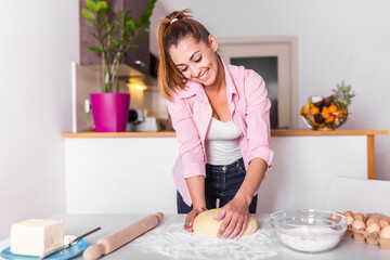 Obraz na płótnie Canvas Young woman knead dough at kitchen, homemade bakery making. Woman kneading dough on kitchen table