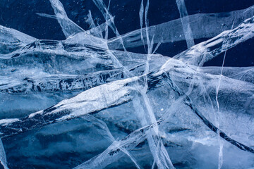 Amazing cracks in the ice of the lake. Blue thick and transparent ice. Horizontal.