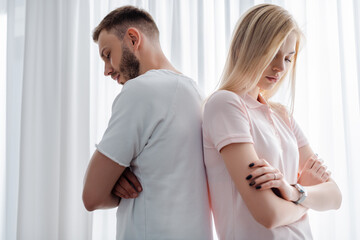 upset man and woman standing with crossed arms, relationship difficulties concept