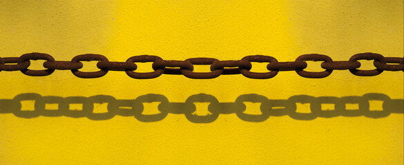 Rusty chain on bright yellow wall