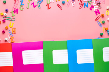 Colorful school exercise books on pink background.