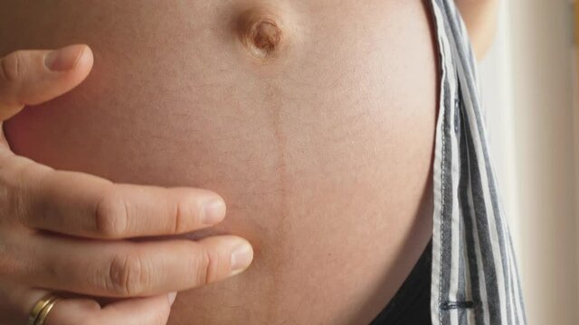 woman shows showing linea negra dark line on pregnancy belly