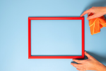 Human hands holding red wooden picture photo frame on blue copy space background.