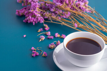 Close-up of a white coffee cup with purple flower blur background.