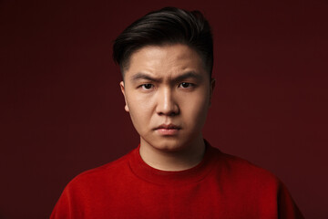 Image of displeased young asian man posing and looking at camera