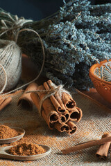 Ground cinnamon, cinnamon sticks, tied with jute rope on old straw bag background in rustic style