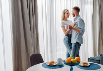 selective focus of happy man holding cup and hugging with cheerful girl