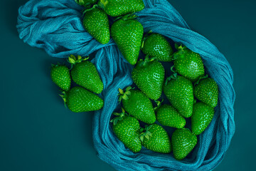 Green strawberries on a blue background with textile elements, creative image of berries, colored...
