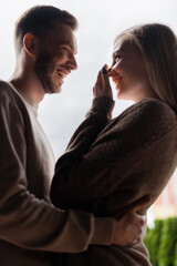 side view of happy man and woman laughing and looking at each other