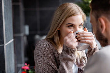 young woman drinking tea and looking at boyfriend