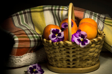 Fototapeta na wymiar group of fresh apricots and pansy in the dark