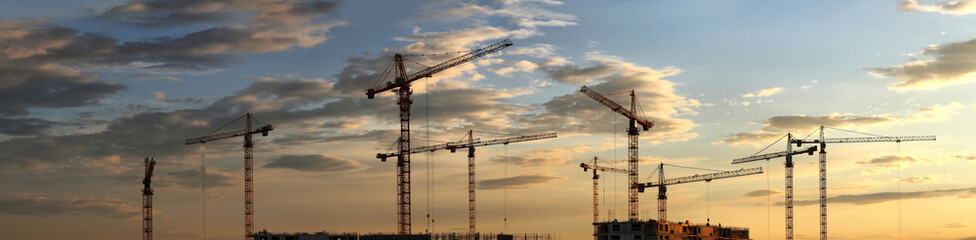 Construction cranes on the background of the sunset
