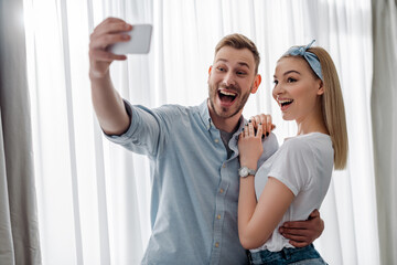 selective focus of excited man taking selfie with cheerful girl