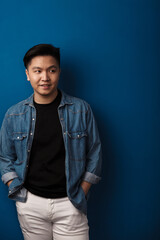 Fototapeta premium Image of pleased handsome asian man smiling and looking aside