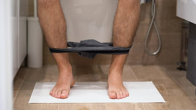 Illness office worker man in gray plaid shirt runs in bath room, moves quickly, wants to go to washroom, put off underwear, grabs, takes white toilet paper close up. Diarrhea attack. Health problems. 