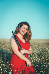woman in a red dress playing the clarinet in a field of daisies
