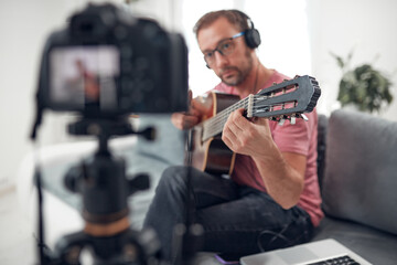 Fototapeta na wymiar Guitarist making video lessons and tutorials for internet vlog website classes.