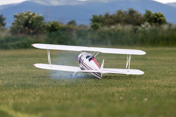 R/C biplane airplane taking off the grass with smoke behind © Michal