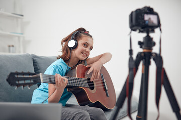 Child guitarist making video lessons and tutorials for internet vlog website classes.
