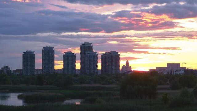 Bucharest city skyline seen from Vacaresti Park Nature Reserve, with skyscraper towers and landmarks Palace of Parliament and People's Salvation Cathedral to the right. Day to night sunset time lapse.