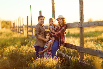 family standing near fence at sunset in village. walks in countryside.