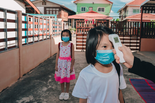 Kids Wearing Mask And Face Shield For Protect And Safety Coronavirus For Back To School, Checking Temperature Body From Infrared Thermometer And Social Distancing Of People Students, Asian Children