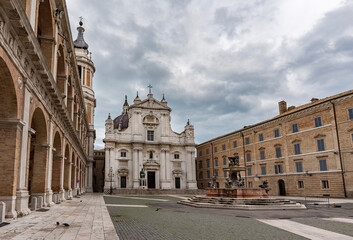Fototapeta na wymiar Italy, Loreto,square of Loreto with background the basilica with cloudy sky, portico to the side, perspective photo
