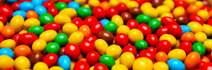 Fototapeta na wymiar Image of colored round sweets. Background of small multicolored dragees. Closeup. Side vew. Banner.