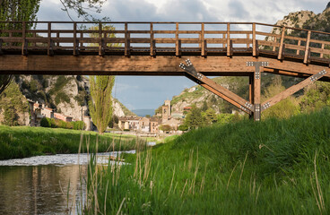 Italy, Macerata, Pioraco, 
wooden bridge,river with river among green meadows in the foreground, country background with cloudy sky