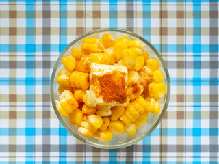 Corn boiled,Butter on top and paprika in glass,Sweet taste,Blue background