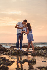 Mom, dad and son. The family strolls along the stony beach by the sea.