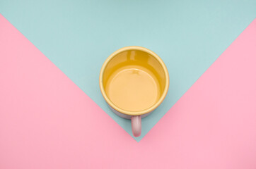 Pink and green enameled mugs on colorful background. Two empty cups on vibrant table.